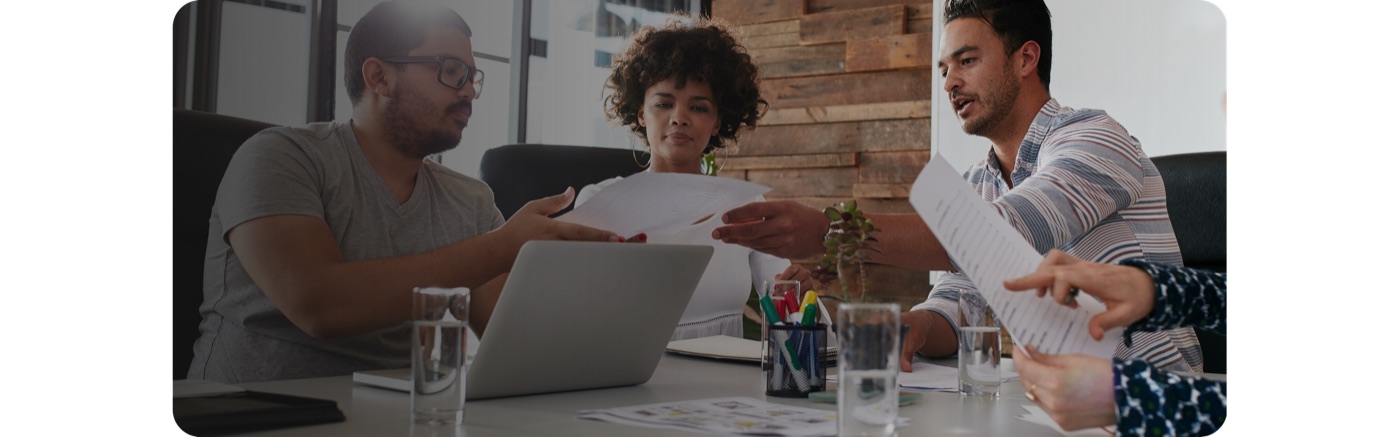 Colleagues passing documents across a meeting table