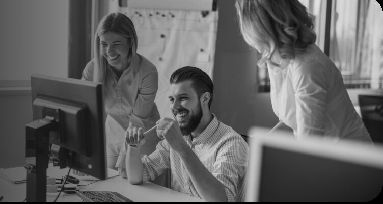 Colleagues smiling at a computer screen in an office